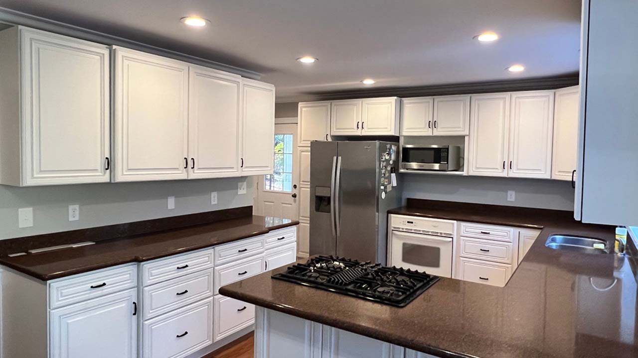 Interior photo of a kitchen with new cabinet painting and island. Track lighting. White cabinets.