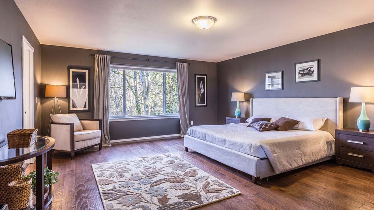 Bedroom with hardwood floors. Dark walls with bright ceiling and track spots.