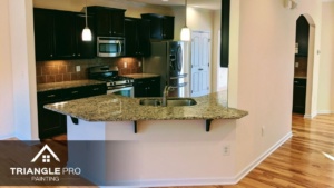 This is a kitchen painting project featuring dark cabinets and granite countertops by Triangle Pro Painting.