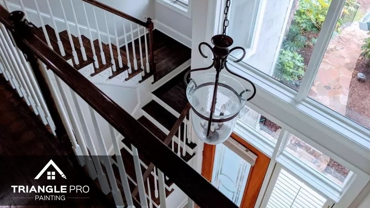This is a stairway painting project with contrasting dark wood and white railings by Triangle Pro Painting.