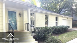This is a front exterior painting of a light-colored brick home by Triangle Pro Painting in Wayland Heights Raleigh.