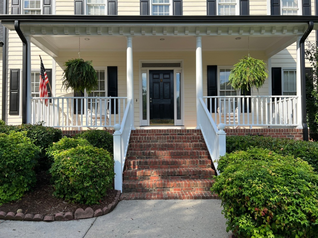 Painter applying moisture-resistant paint to a Raleigh home exterior