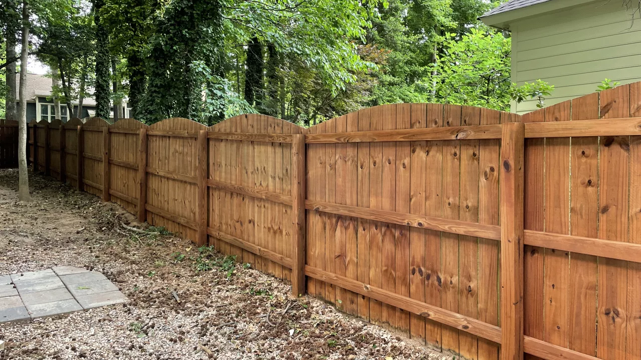 A fence that is newly stained using brown stain on Raleigh, NC.