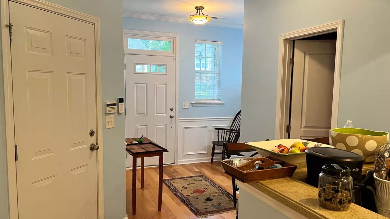 Interior painting of the entry way to a home Warm tones and sunlight highlight the image.