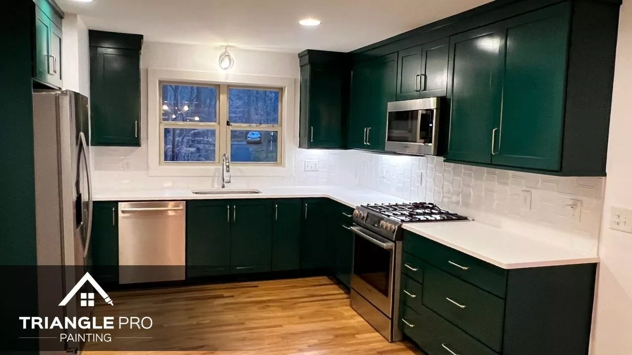 A stylish kitchen with dark green cabinets and white walls, finished with a crisp backsplash.