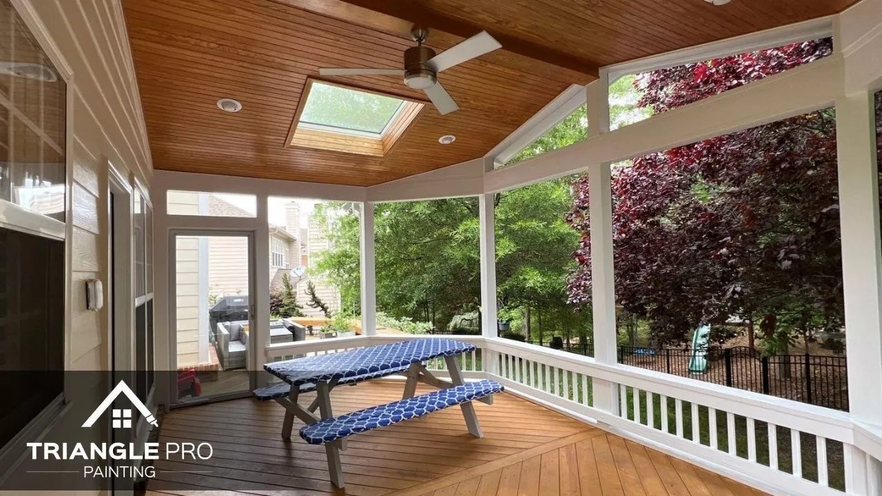 A beautifully painted screened porch with wood ceilings and clean white trim.