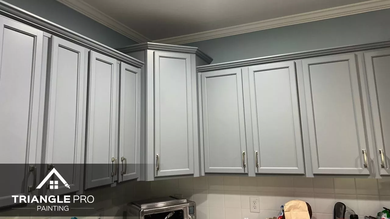 This is a kitchen featuring newly painted gray cabinets with white crown molding in Wayland Heights Raleigh, NC.
