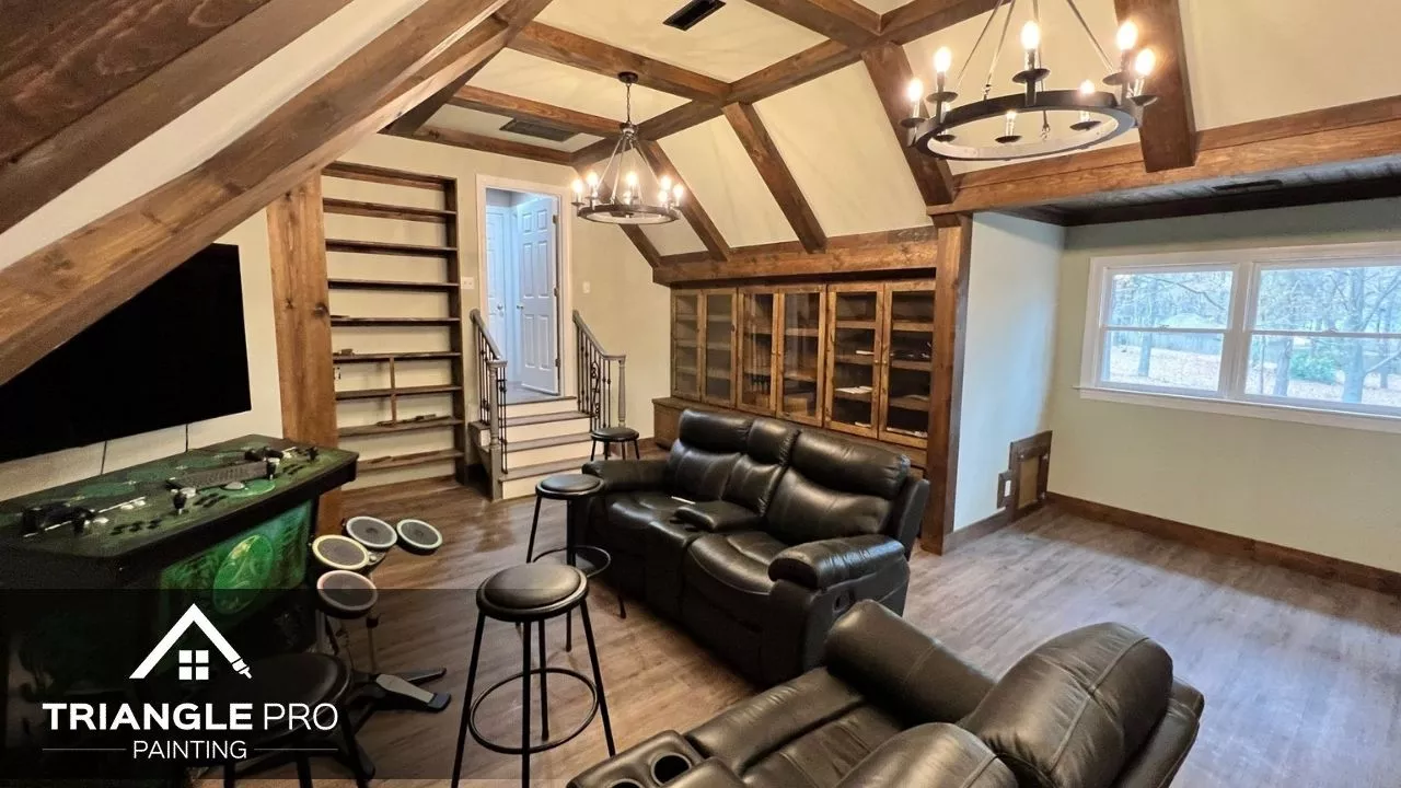 A warm, rustic-style media room with soft wall tones and exposed wood beams.