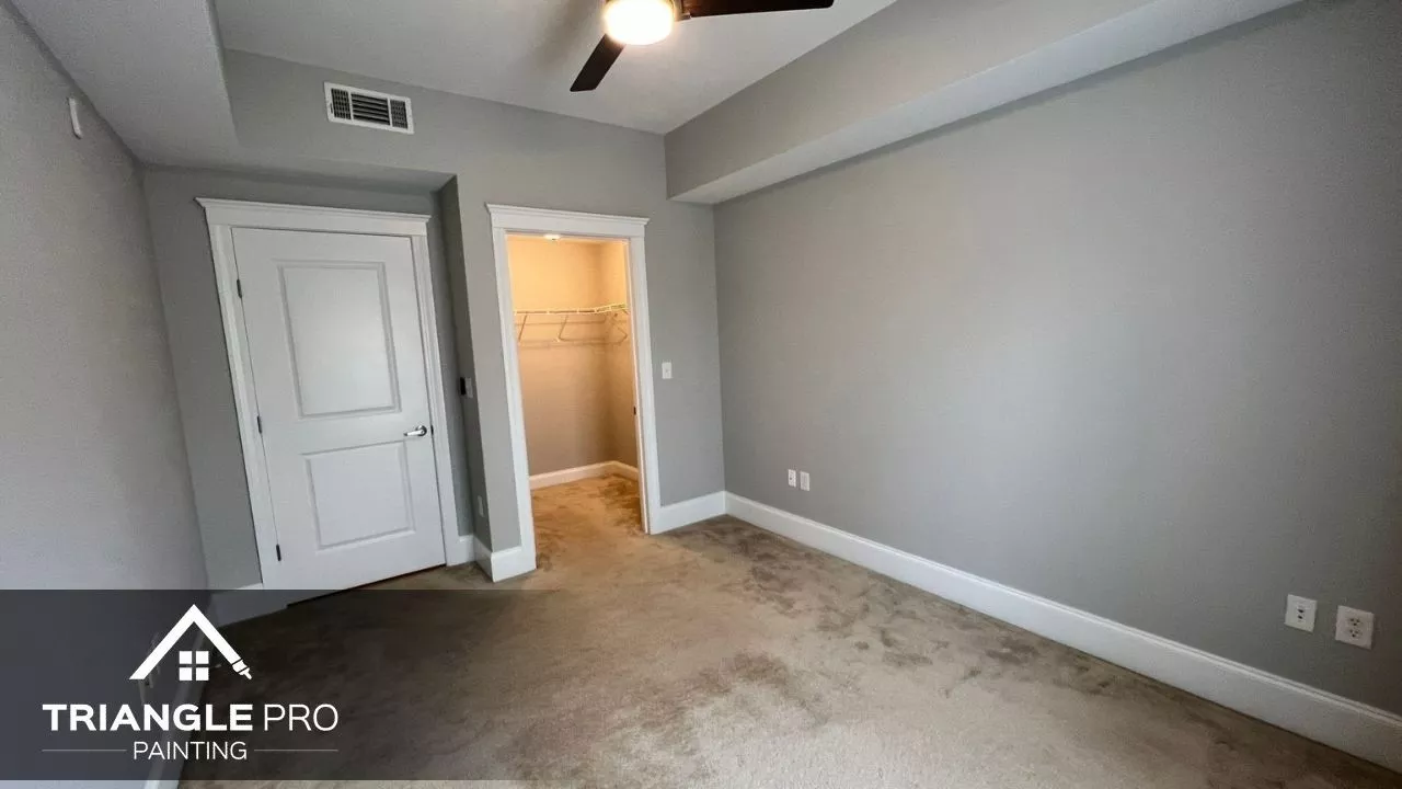This image shows a simple gray-painted bedroom with crisp white trim and door details, a project by Triangle Pro Painting in Umstead Raleigh NC.