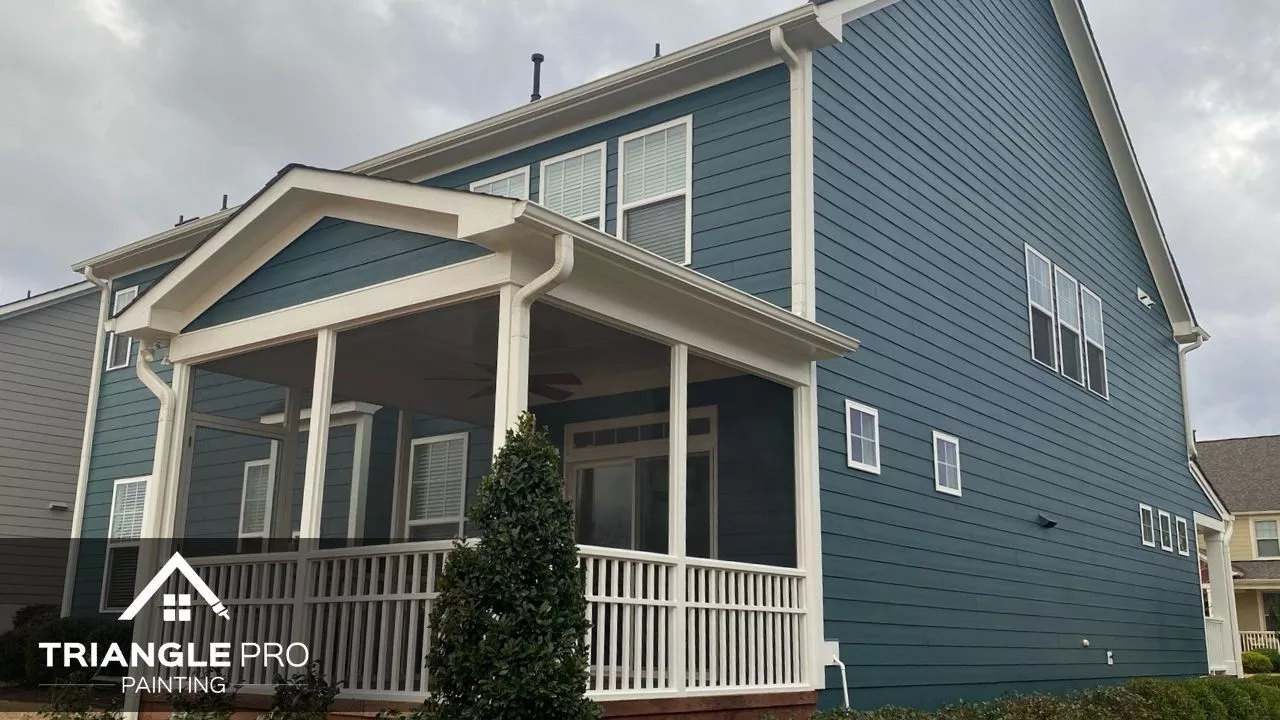 This photo captures a freshly painted home exterior in deep blue with white trim, completed by Triangle Pro Painting in Umstead Raleigh NC.