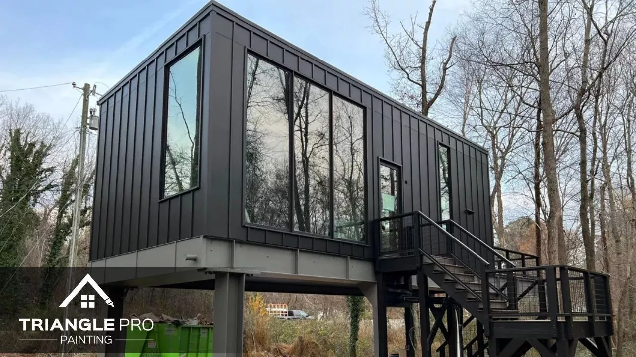 This image shows the exterior of a modern black elevated home in Madonna Acres painted by Triangle Pro Painting.