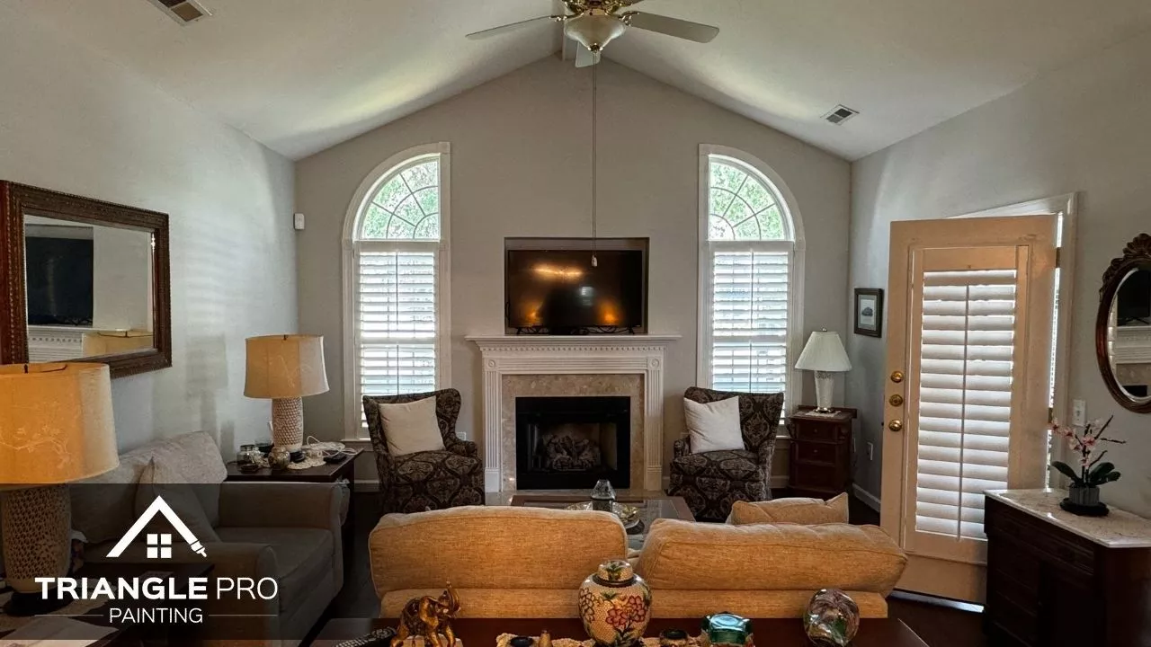 This image shows a clean and bright living room with vaulted ceilings and a fireplace, freshly painted by Triangle Pro Painting in Boylan Heights Raleigh, NC.